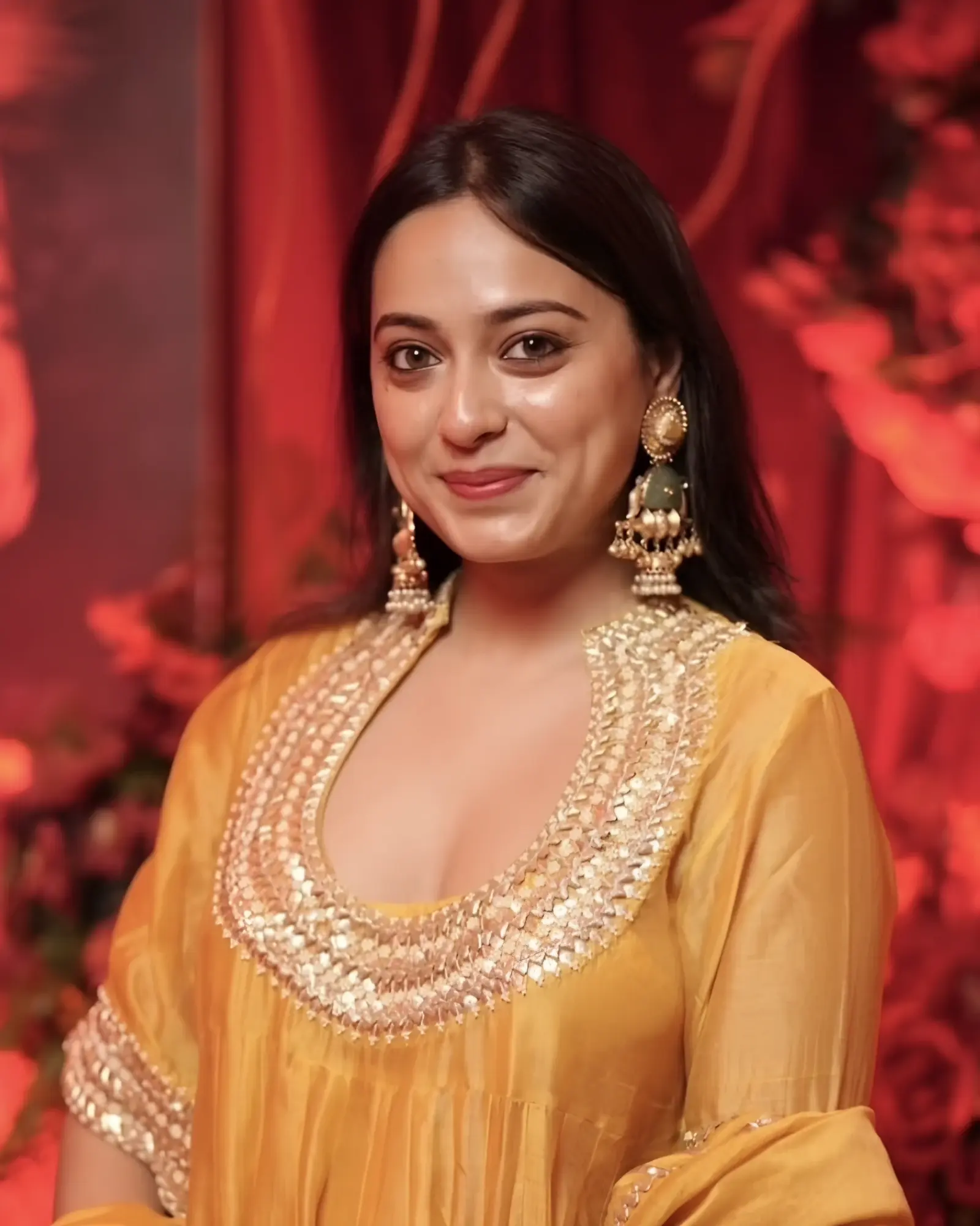 Parnika Harde, founder of La Reiné, smiling, in a saffron silk kurta with gold embroidery and gold jhumka earrings